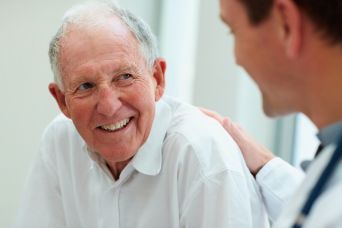 medico tocca la spalla di un uomo anziano che lo guarda 